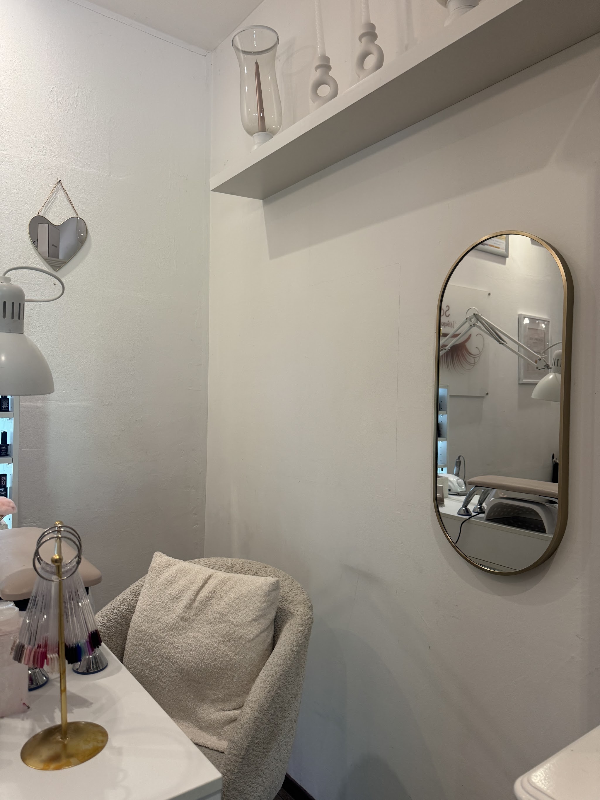 De salon van Dominique: witte nageltafel, lamp, kleurwaaier en een gouden ovale spiegel